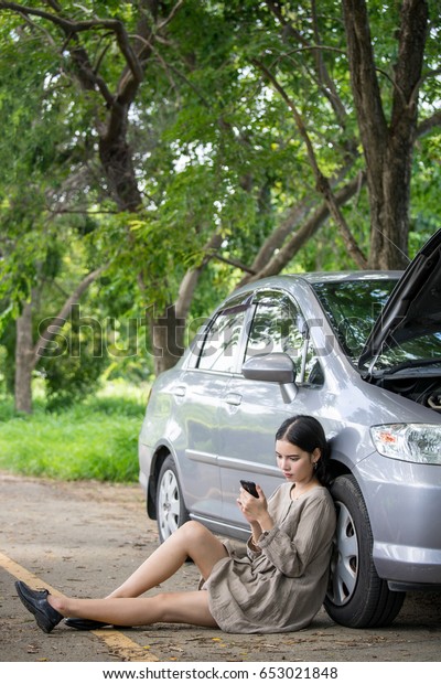 Young woman using smart\
phone call mechanic car service ,auto engine crash with alone woman\
concept.