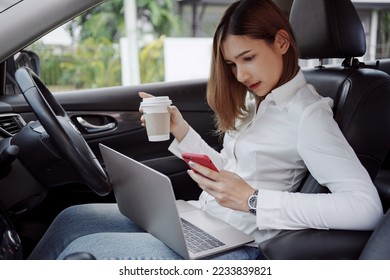 Young woman using smartphone and drinks coffee inside a car. Multitasking.