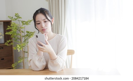 A young woman using a smartphone at home