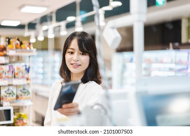 Young Woman Using Smartphone Payment At A Supermarket