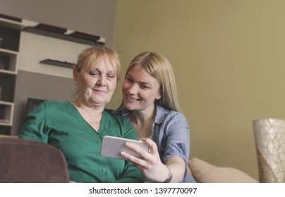 Young woman using smartphone,making picture with senior mother.