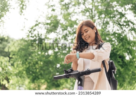 Young woman using smartwatch while riding a bicycle in the park.