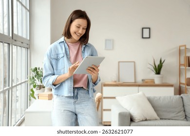 Young woman using tablet computer near window at home