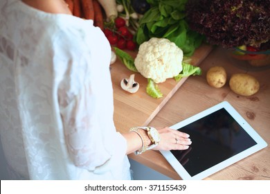 Young woman using a tablet computer to cook in her kitchen - Powered by Shutterstock