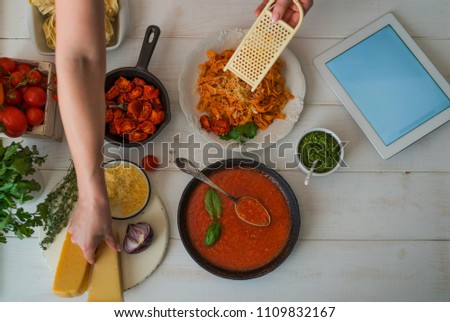 Young woman using a tablet computer to cook in her kitchen. Cook healthy food. Woman housewife cooks food a recipe from the Internet with a tablet computer in the kitchen. Soft focus.
