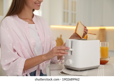 Young Woman Using Toaster At Table In Kitchen, Closeup