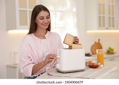Mujer joven usando tostadora en la mesa en la cocina