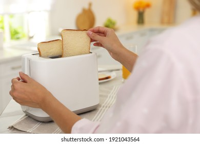 Young Woman Using Toaster At Table In Kitchen, Closeup