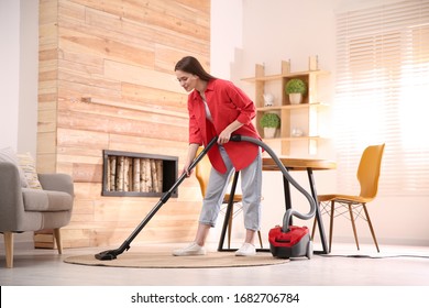 Young Woman Using Vacuum Cleaner At Home