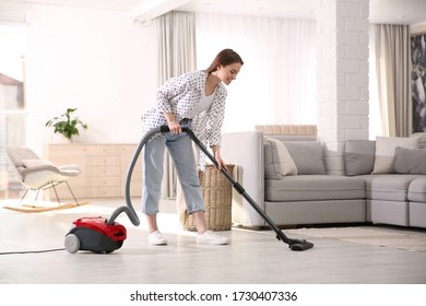 Young Woman Using Vacuum Cleaner At Home