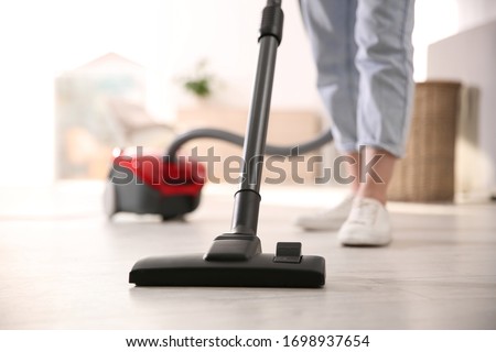 Young woman using vacuum cleaner at home, closeup Сток-фото © 