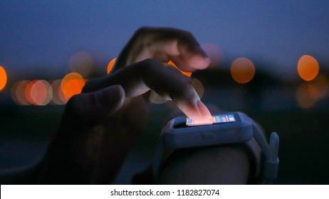 Young woman using wearable smartwatch computer device in the city. Evening time, twilight. Relax, entertainment and technology concept - Powered by Shutterstock