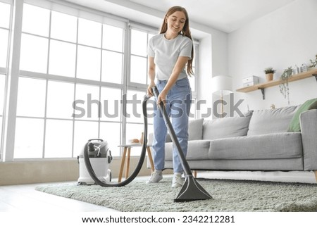 Young woman vacuuming carpet at home Сток-фото © 