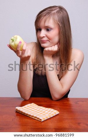 young woman with a vegetable sitting at a table
