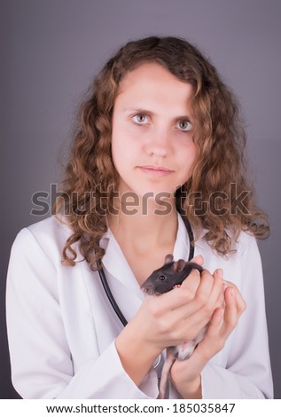 Young woman veterinarian looks at the rat