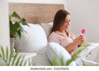 Young woman with vibrator in bed