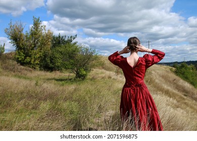 Young Woman In Vintage Red Dress From The Back In A Valley