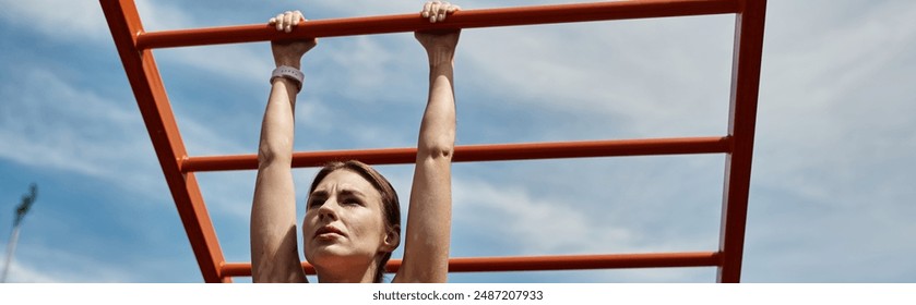 A young woman with vitiligo in a pink crop top hangs from a set of monkey bars in an outdoor park. - Powered by Shutterstock