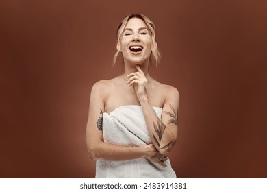 A young woman with vitiligo stands wrapped in a towel, smiling and looking confident. The beige background emphasizes her natural beauty. - Powered by Shutterstock