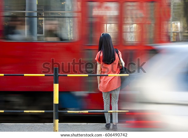 Young woman waiting at bus stop and city traffic  in\
motion blur