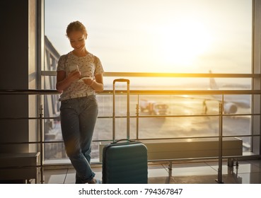 young woman waiting for  flying  at airport  at window  with a suitcase  