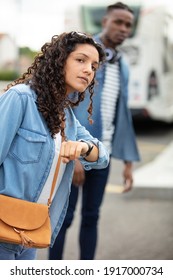 young woman waits at bus station looks at watch