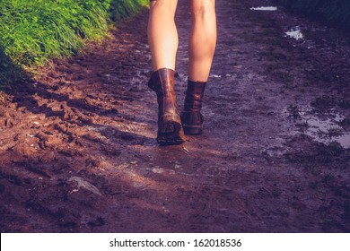 Young Woman Walking Along Muddy Trail