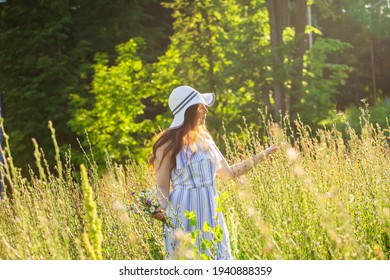 Young woman walking among wildflowers on sunny summer day. Concept of the joy of communicating with summer nature