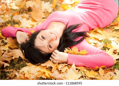 Young Woman Walking In The Autumn Park. Beauty Nature Scene With Colorful Foliage Background, Yellow Trees And Leaves At Fall Season. Autumn Outdoor Lifestyle. Happy Smiling Woman Relax On Fall Leaves