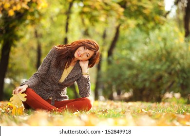 Young Woman Walking In The Autumn Park. Beauty Nature Scene With Colorful Foliage Background, Yellow Trees And Leaves At Fall Season. Autumn Outdoor Lifestyle. Happy Smiling Woman Relax On Fall Leaves