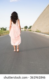 young woman walking barefoot on the road