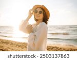 Young woman walking by beach at golden sunset - Female tourist on summer vacation.