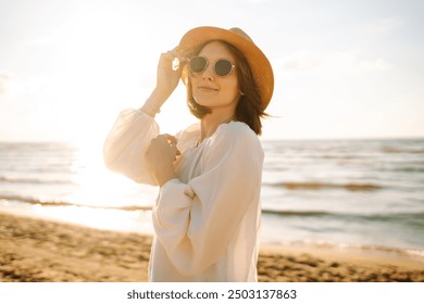 Young woman walking by beach at golden sunset - Female tourist on summer vacation. - Powered by Shutterstock