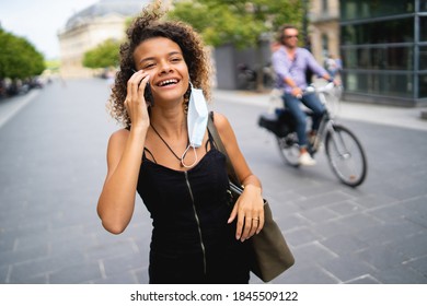 Young Woman Walking In The City Wearing A Surgical Mask The Wrong Way And Talking On The Phone