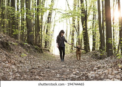 Young Woman Walking With Dog In Forest