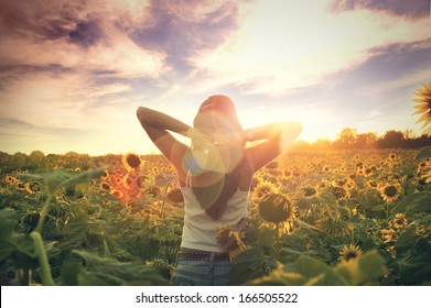 Young Woman Walking In The Field With Sunflowers