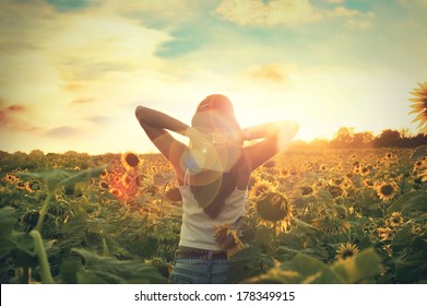 Young Woman Walking In The Field With Sunflowers