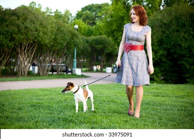 Young Woman Walking With Her Dog In A Park