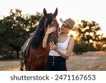 young woman walking with her horse in the countryside as the sun sets behind her. The image conveys sense of freedom and connection with nature