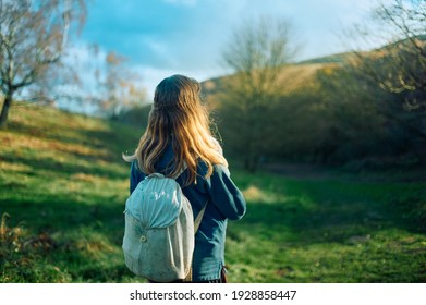A young woman is walking in a meadow and woodland on a sunny autumn day