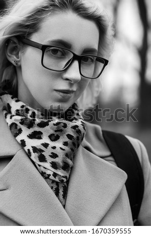 young woman walking at old autumn park, looking at camera, smiling, monochrome