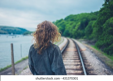 A Young Woman Is Walking On The Railroad Tracks