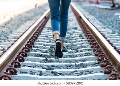 A Young Woman Is Walking On The Railroad Tracks