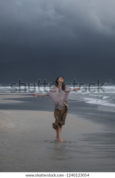 雨の日に 濃い暗雲の前で嵐の海岸を歩く若い女性 の写真素材 今すぐ編集