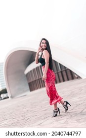 Young Woman Is Walking On The Street During Talking By Phone And Turning Her Head To Look Back. Connecting People Concept