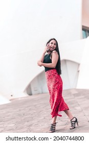 Young Woman Is Walking On The Street During Talking By Phone And Turning Her Head To Look Back. Connecting People Concept