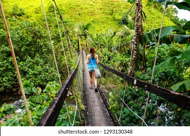 Young woman walking on suspension bridge over Wainibau stream, Lavena Coastal Walk, Taveuni Island, Fiji. Taveuni is the third largest island in Fiji.