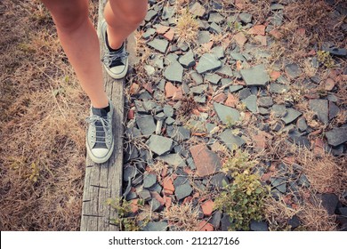 A Young Woman Is Walking On A Wooden Beam Outside