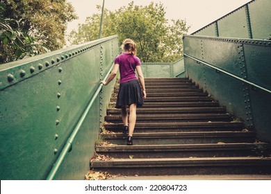 A Young Woman Is Walking Up Stairs Outside In A Park