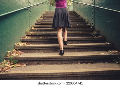 A Young Woman Is Walking Up Stairs Outside In A Park